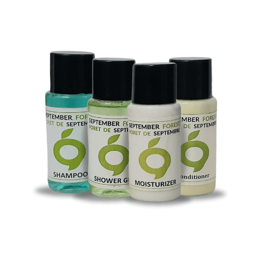 A collection of black September Forest hotel toiletries, including moisturizer, shampoo, conditioner, and shower gel.