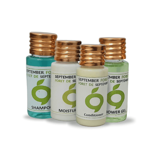 A collection of black September Forest hotel toiletries, including moisturizer, shampoo, conditioner, and shower gel.